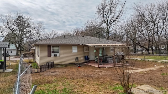 back of house featuring a fenced backyard and a shingled roof