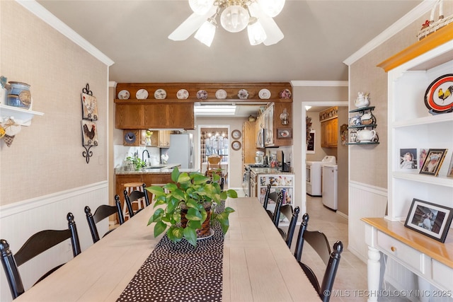 dining area featuring washer and dryer, a wainscoted wall, and crown molding