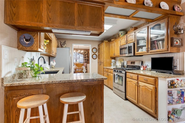 kitchen with a breakfast bar, a sink, stainless steel appliances, a peninsula, and glass insert cabinets