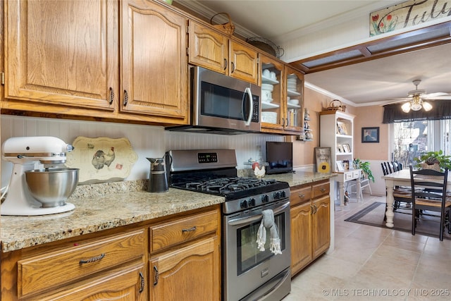 kitchen featuring light stone counters, stainless steel appliances, crown molding, and ceiling fan