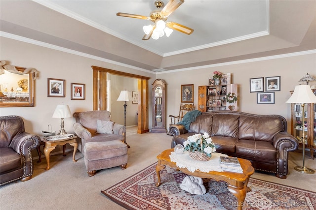 living area with a raised ceiling, light carpet, crown molding, and ceiling fan