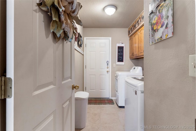 laundry area featuring cabinet space, a textured ceiling, light tile patterned flooring, and washer and clothes dryer