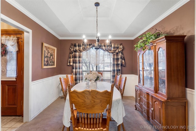 carpeted dining room featuring a chandelier, wainscoting, and a raised ceiling