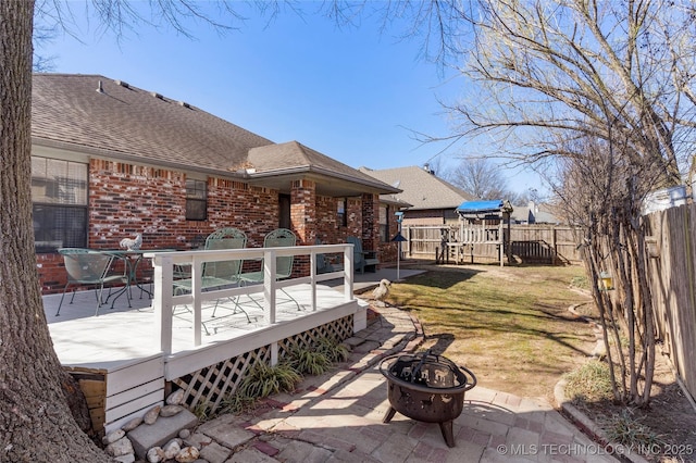 exterior space featuring a patio area, a fire pit, a wooden deck, and fence