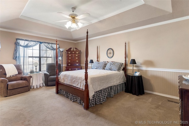 carpeted bedroom featuring visible vents, a ceiling fan, crown molding, and a tray ceiling