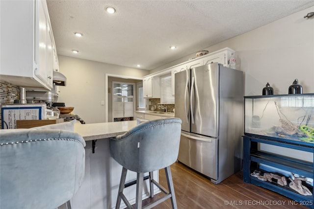 kitchen with backsplash, white cabinets, dark wood-style flooring, and freestanding refrigerator