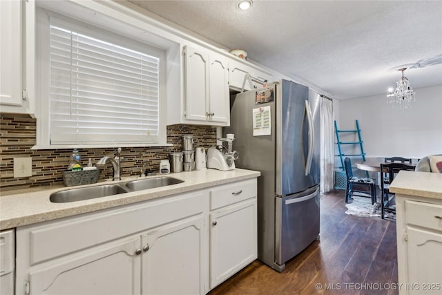 kitchen featuring dark wood-style flooring, white cabinetry, freestanding refrigerator, and a sink