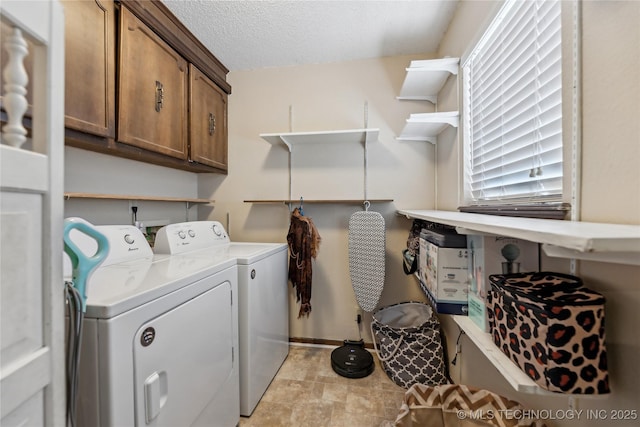 laundry room featuring baseboards, cabinet space, a textured ceiling, and washing machine and dryer