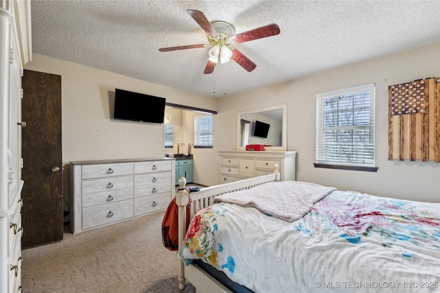 bedroom with multiple windows, carpet, and a textured ceiling