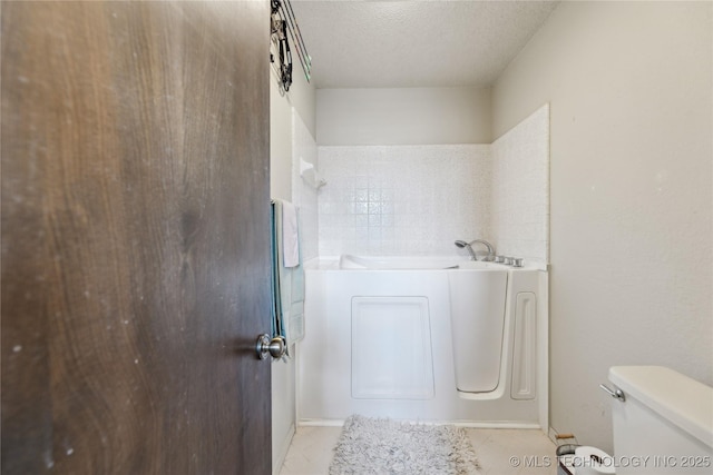 full bathroom featuring a garden tub, toilet, and a textured ceiling