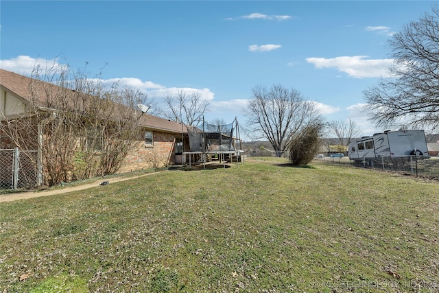 view of yard with a trampoline and fence