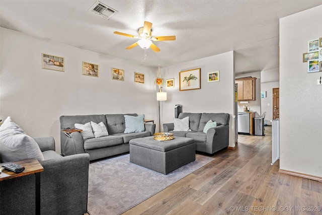 living area with visible vents, wood finished floors, and a ceiling fan