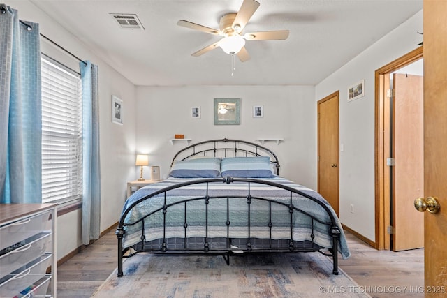 bedroom featuring multiple windows, wood finished floors, visible vents, and baseboards