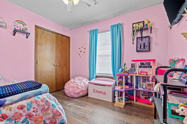 bedroom with a ceiling fan, wood finished floors, and a closet