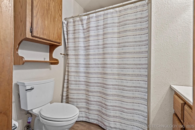 full bath featuring vanity, curtained shower, toilet, and a textured wall