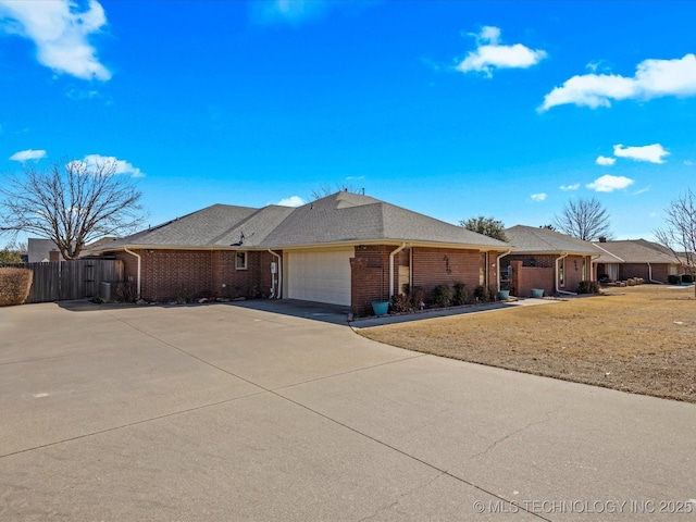 ranch-style house featuring fence, roof with shingles, concrete driveway, a garage, and brick siding