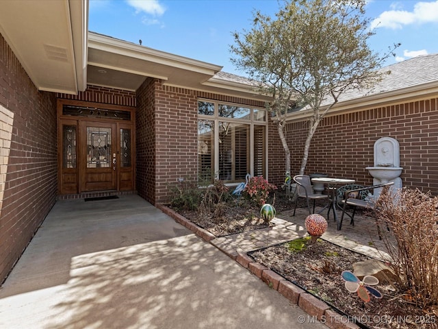 doorway to property with a patio area and brick siding