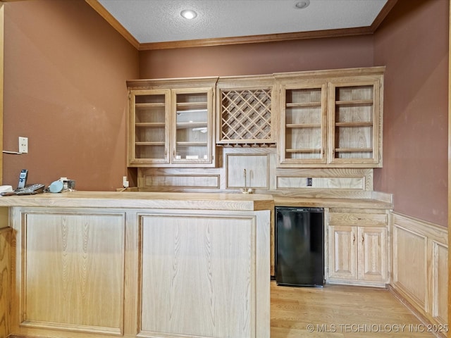 bar with indoor wet bar, crown molding, refrigerator, and light wood-type flooring