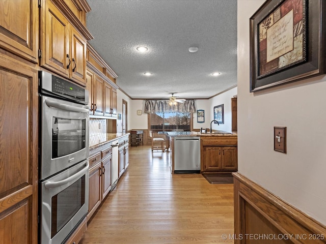 kitchen featuring a sink, stainless steel appliances, brown cabinets, and ornamental molding