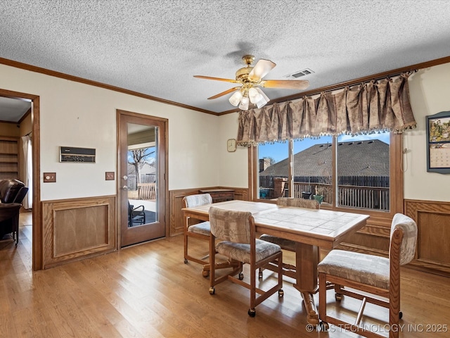 dining room with a healthy amount of sunlight, visible vents, and wainscoting