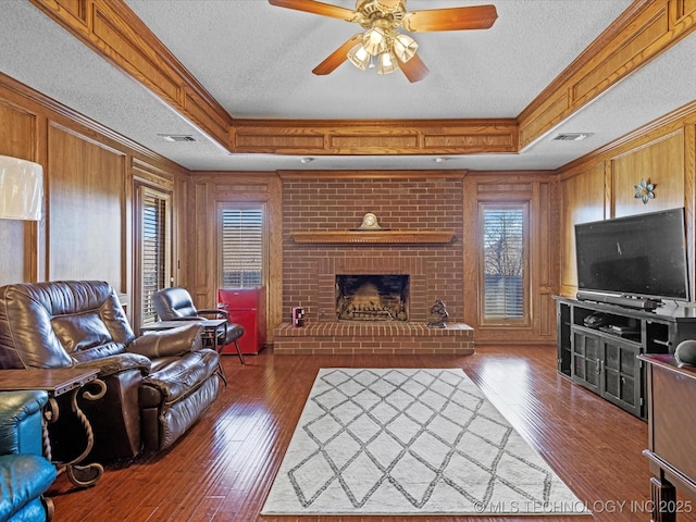 living room featuring a raised ceiling, a ceiling fan, and crown molding