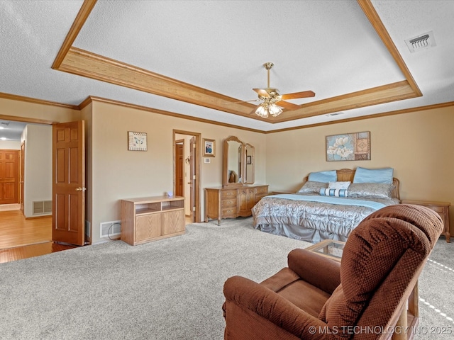 carpeted bedroom featuring visible vents, a raised ceiling, and crown molding