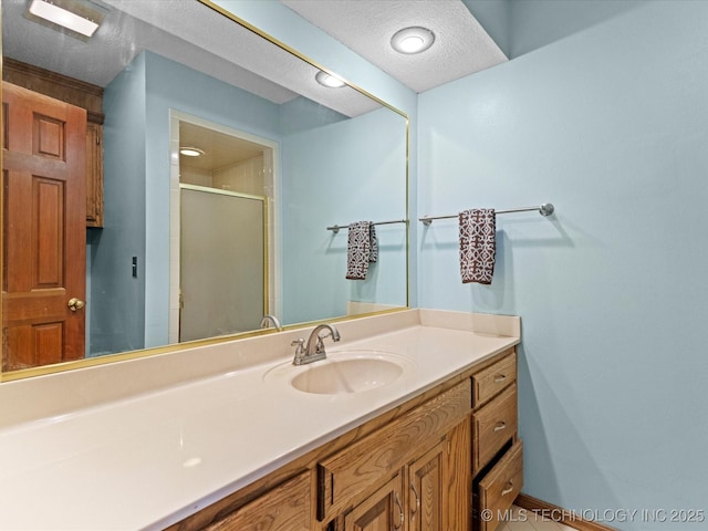 bathroom with vanity, a shower stall, and a textured ceiling