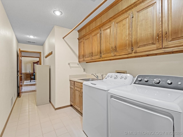 laundry room featuring visible vents, a sink, a textured ceiling, cabinet space, and separate washer and dryer