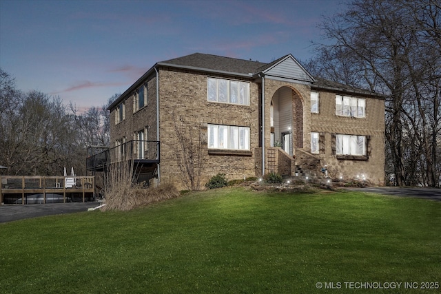 traditional-style house featuring brick siding, driveway, and a yard