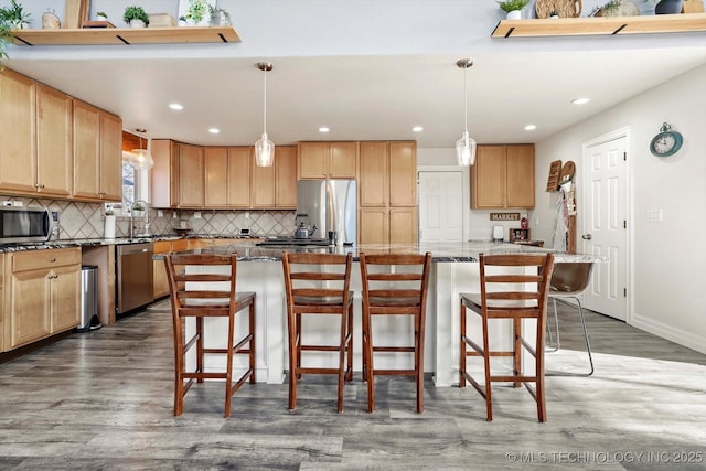 kitchen featuring a sink, stainless steel appliances, wood finished floors, and decorative backsplash