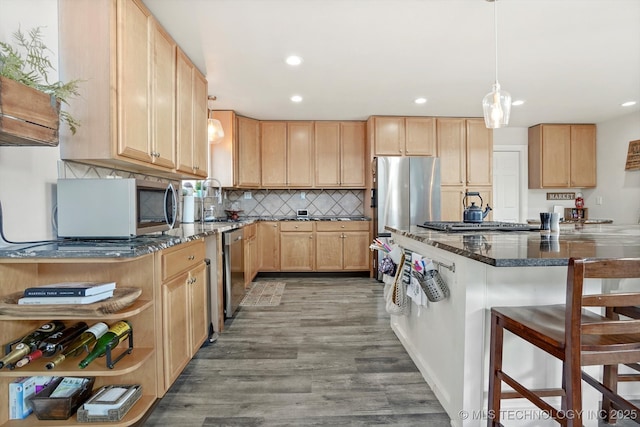 kitchen featuring backsplash, light brown cabinetry, a breakfast bar, light wood-type flooring, and appliances with stainless steel finishes