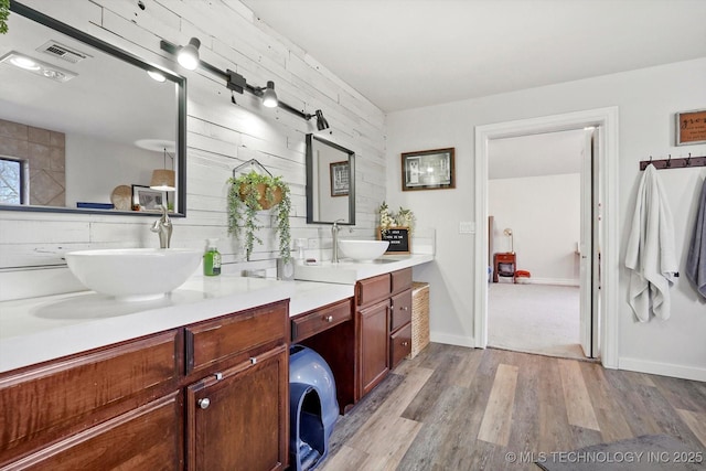 bathroom with a sink, visible vents, wood finished floors, and double vanity