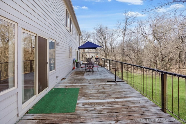 deck featuring outdoor dining space and a lawn