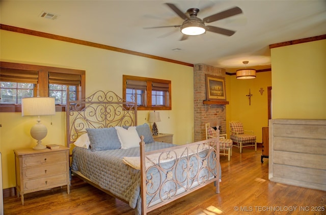 bedroom featuring visible vents, ornamental molding, ceiling fan, and wood finished floors