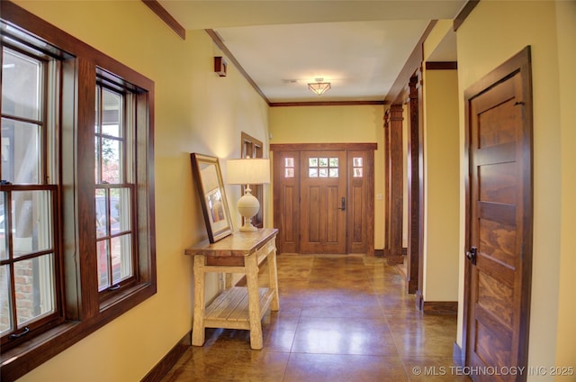 foyer entrance with dark tile patterned floors, baseboards, and ornamental molding