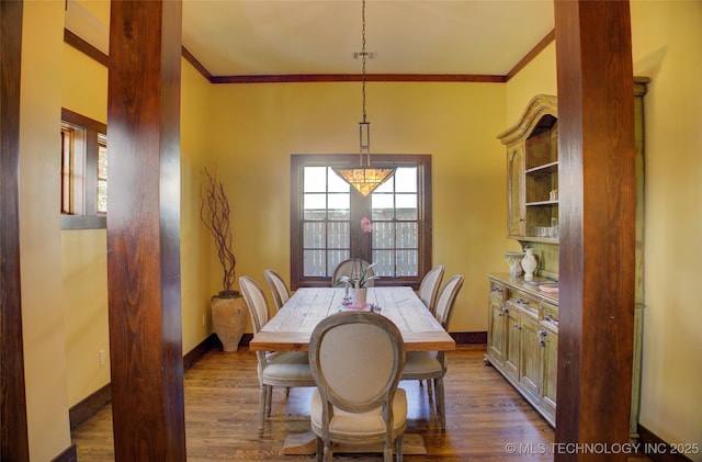 dining room with a wealth of natural light, dark wood finished floors, and ornamental molding