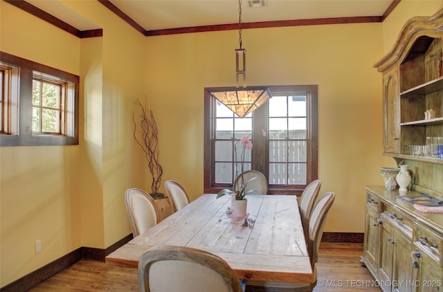 dining room with visible vents, baseboards, wood finished floors, and ornamental molding