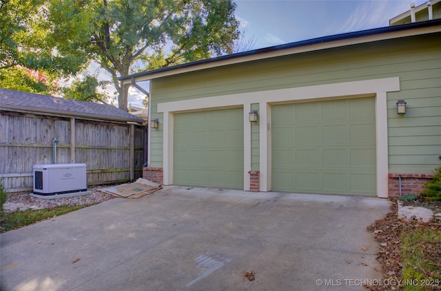 garage featuring driveway and fence