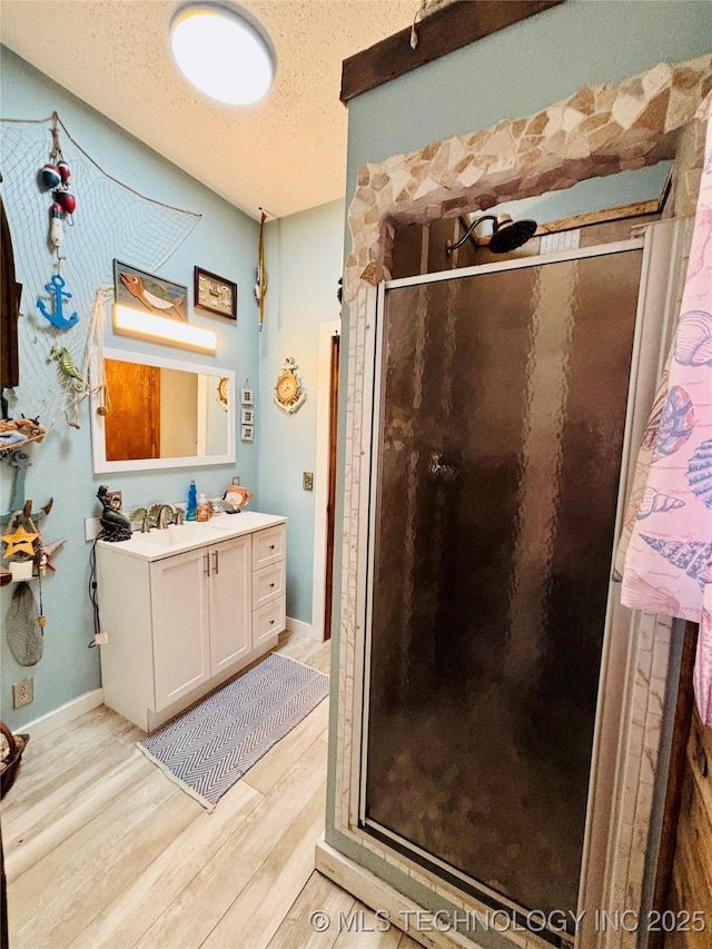 bathroom with vanity, a shower stall, wood finished floors, and a textured ceiling