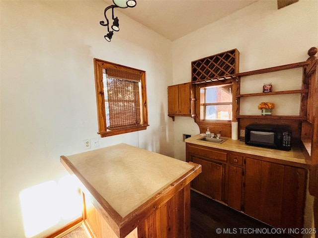 kitchen with brown cabinetry, a peninsula, light countertops, and a sink