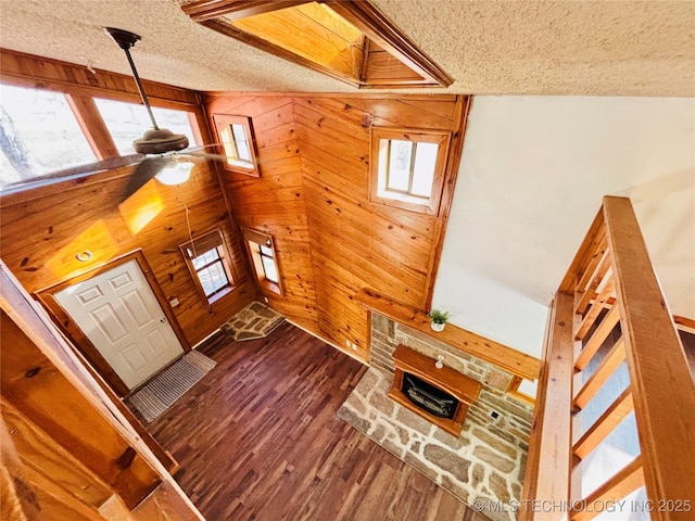 interior space with dark wood finished floors, wooden walls, a textured ceiling, and stairs