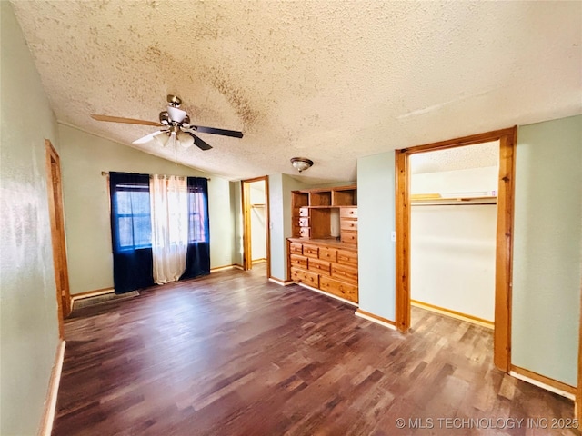 unfurnished bedroom with dark wood finished floors, lofted ceiling, baseboards, and a textured ceiling