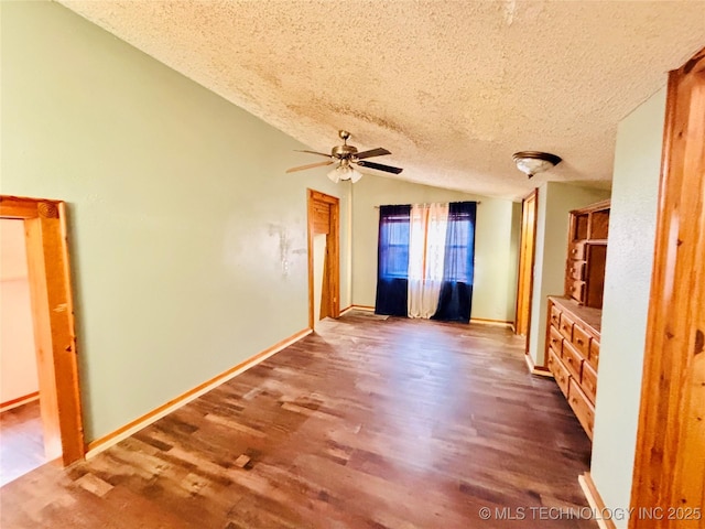 interior space with wood finished floors, baseboards, lofted ceiling, ceiling fan, and a textured ceiling