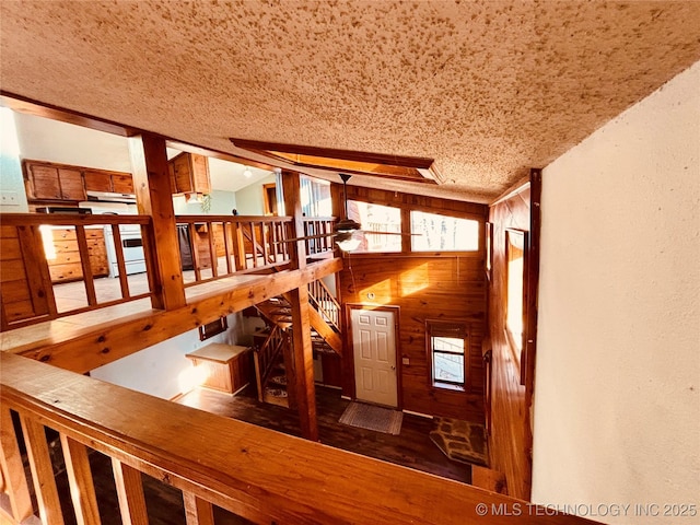 stairs featuring lofted ceiling, a textured ceiling, and wood walls