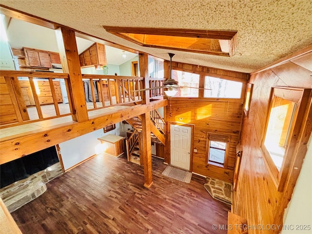 interior space with lofted ceiling, wood finished floors, wood walls, and a healthy amount of sunlight