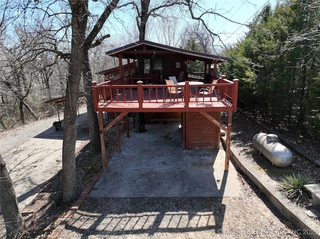 back of house featuring driveway and a wooden deck