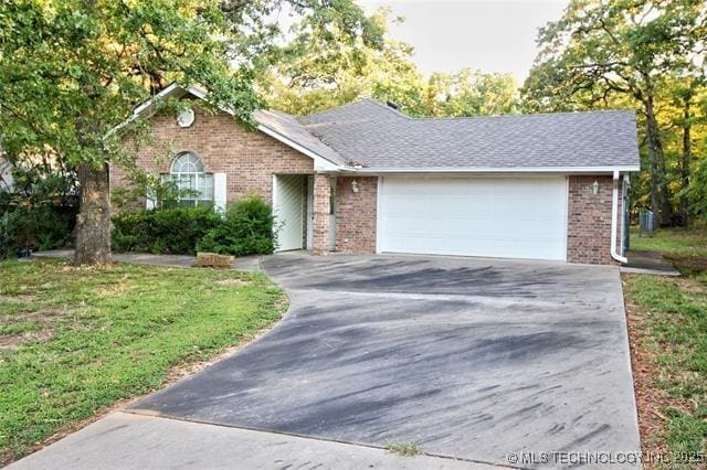 ranch-style home featuring brick siding, concrete driveway, a garage, and a front yard