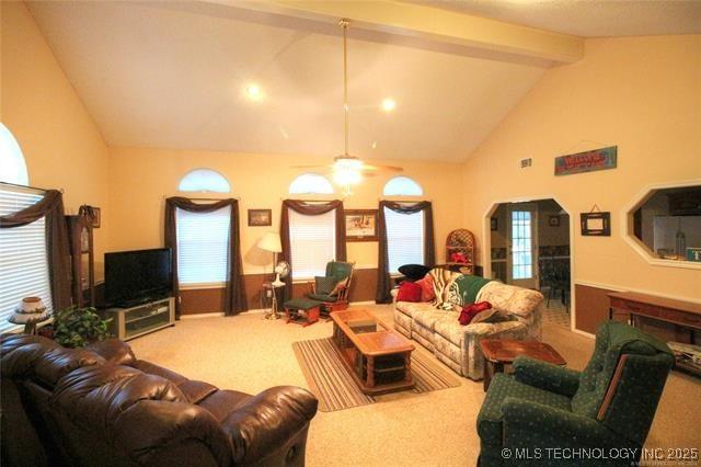 carpeted living area with beam ceiling, a healthy amount of sunlight, high vaulted ceiling, and a ceiling fan