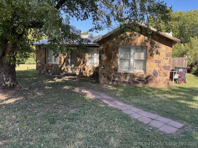 view of side of property featuring stone siding and a yard