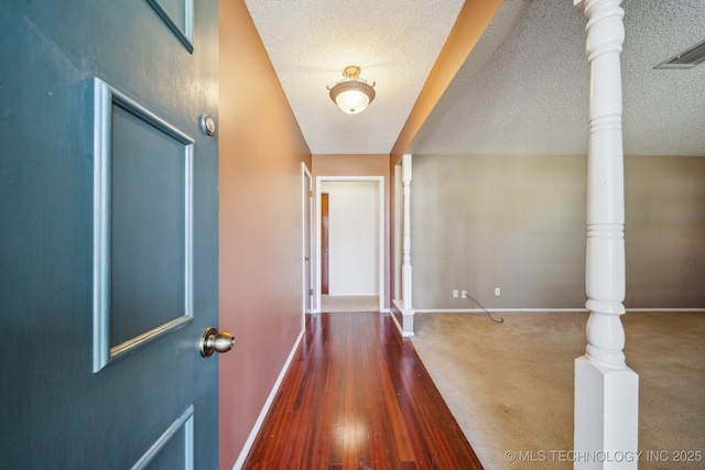 corridor with wood finished floors, baseboards, and a textured ceiling